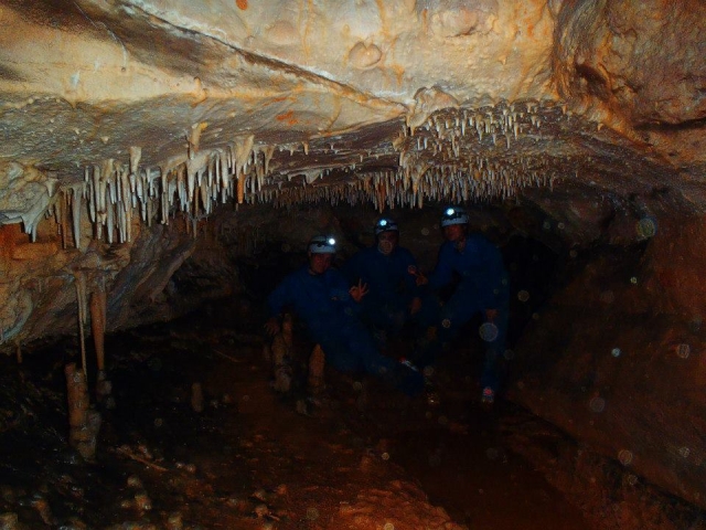  Three people greet the camera inside the cave 